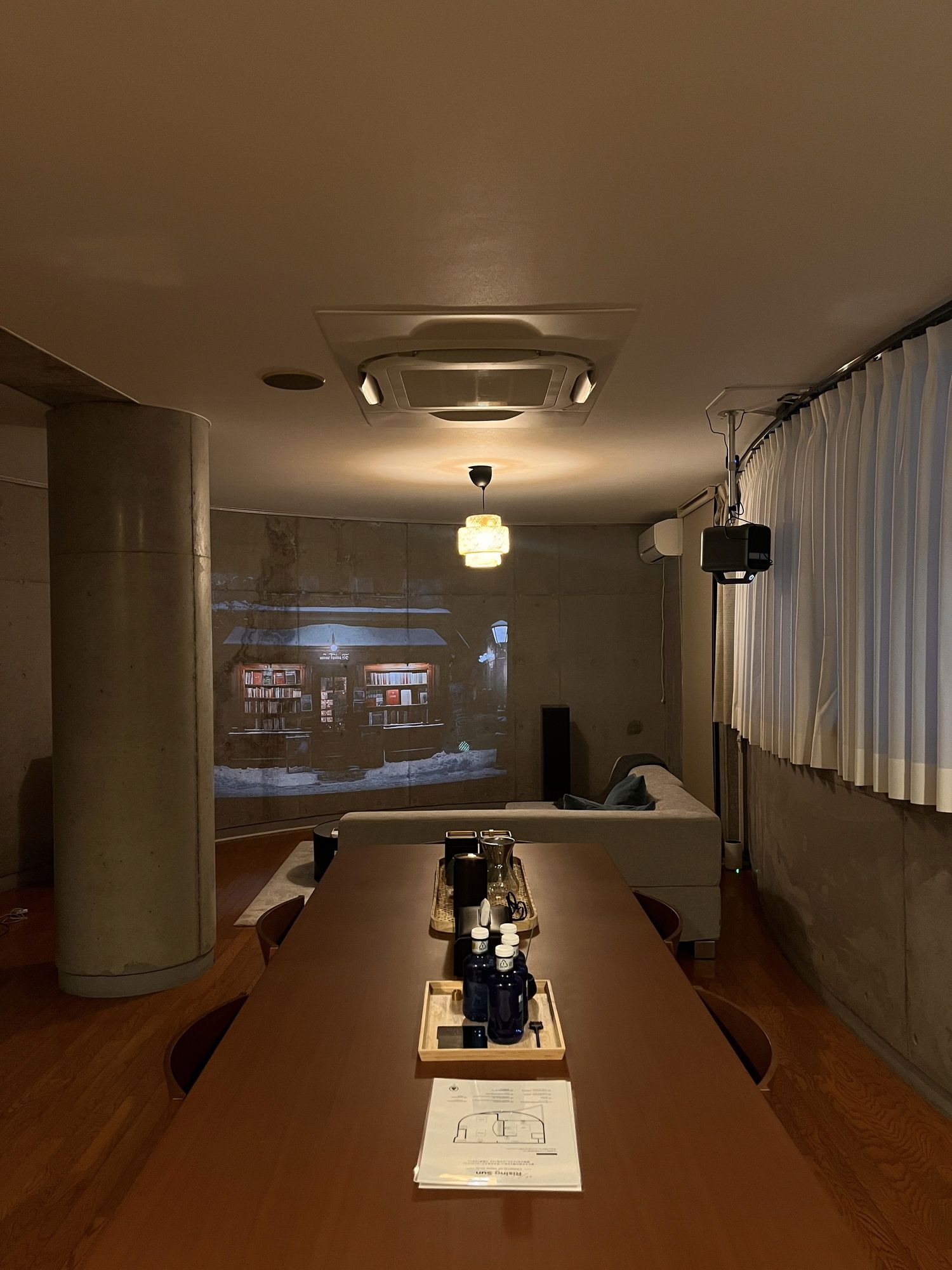 Long communal table in a narrow dining room, night beyond the window