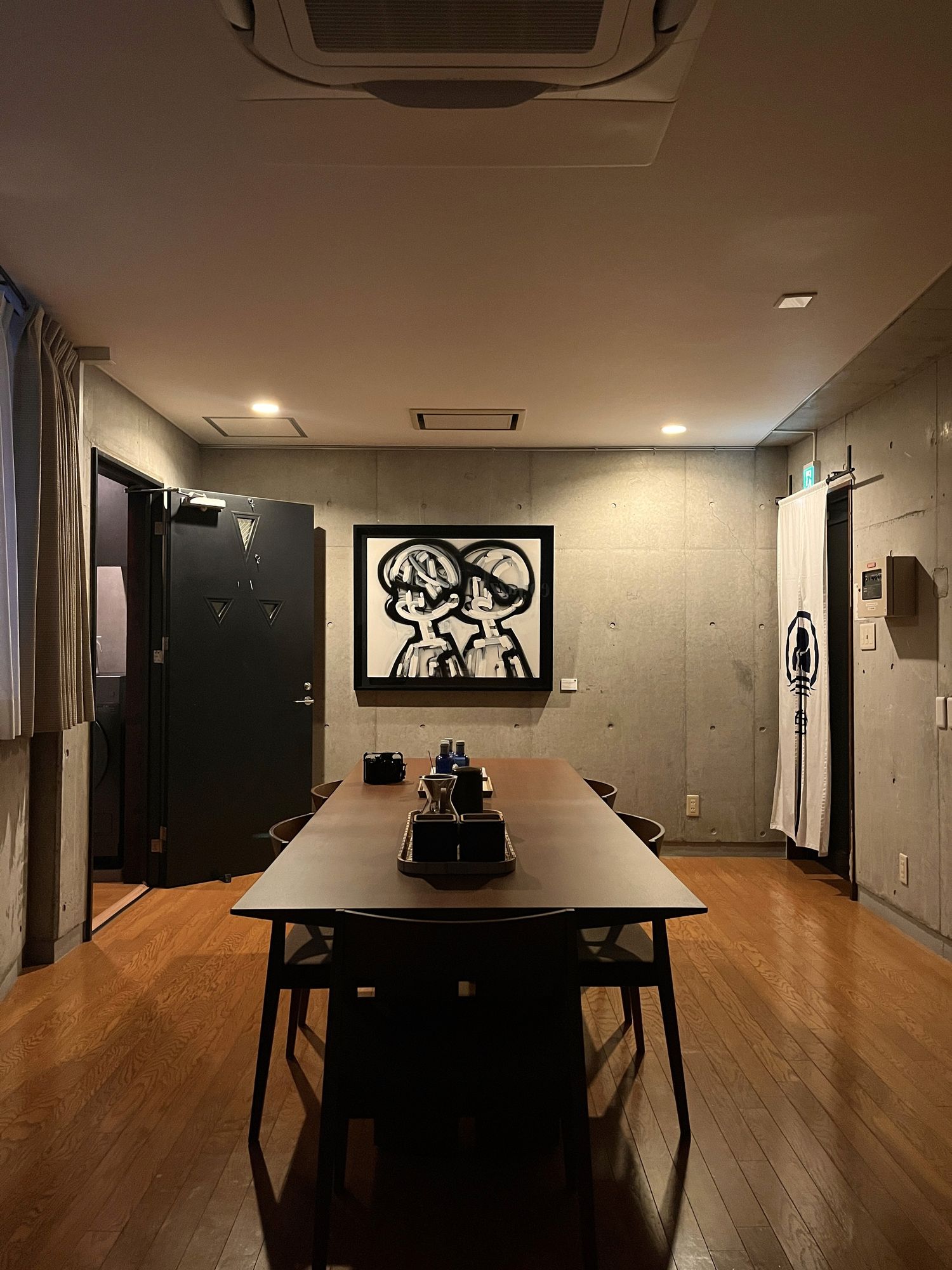 Dining table beneath a framed drawing in a dark corridor room