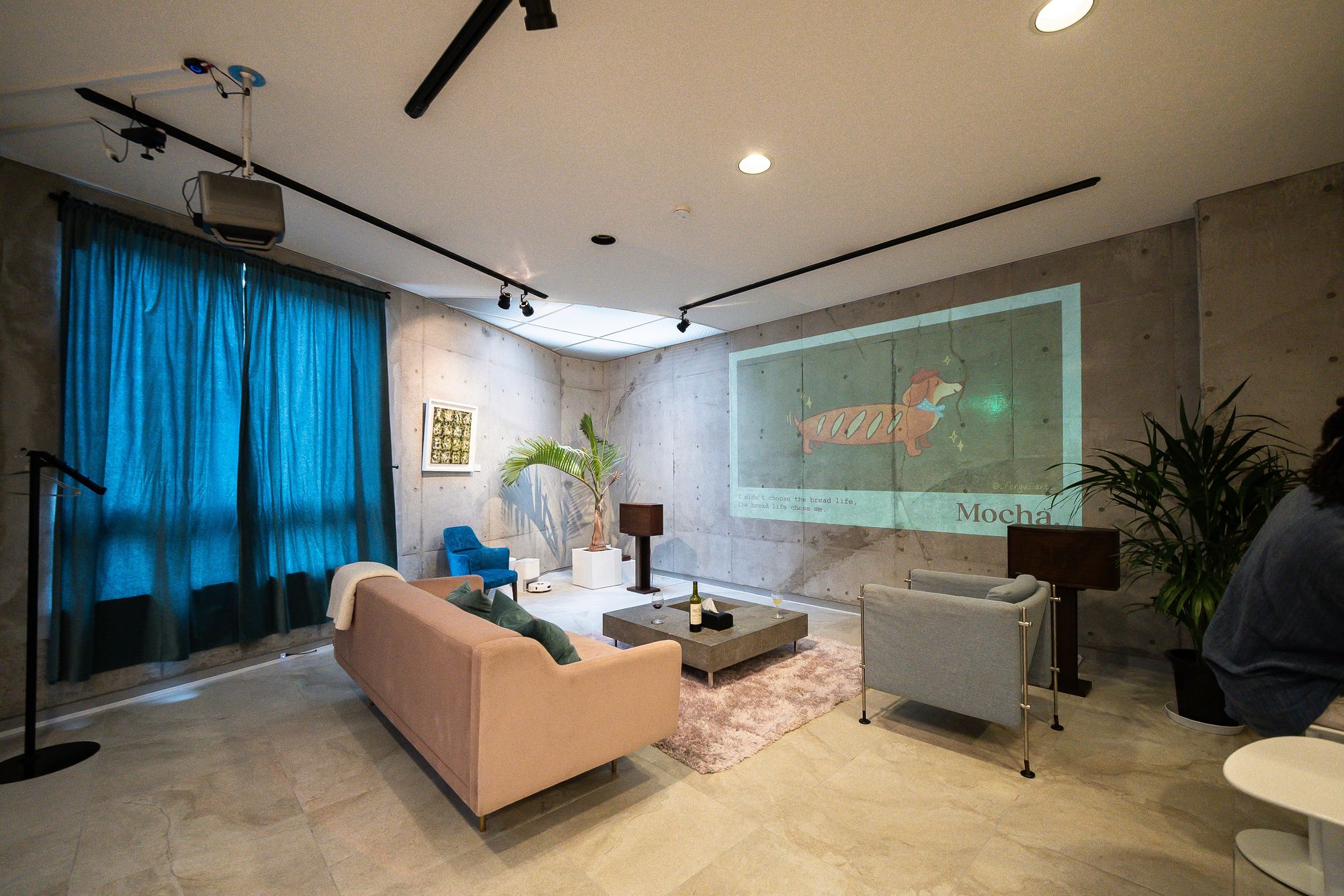 Lounge with concrete walls, blue curtains and projected artwork