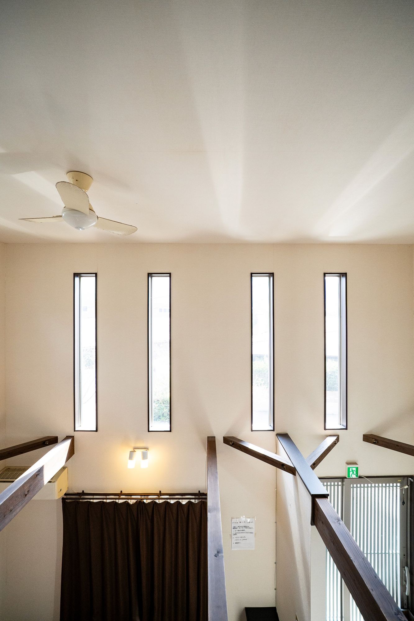 Room lit by four tall narrow windows above dark curtains