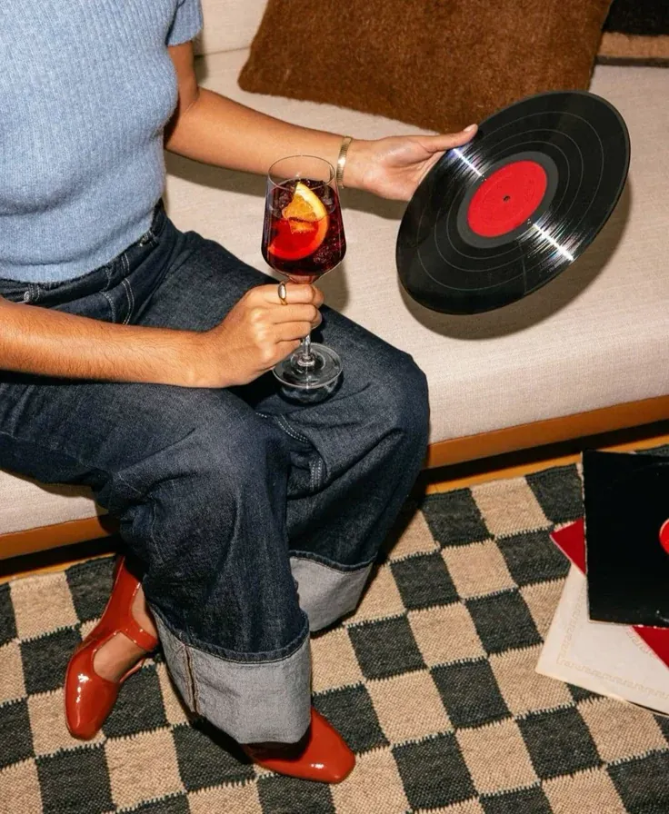 Guest holding a vinyl record and a glass of wine on a checkered rug