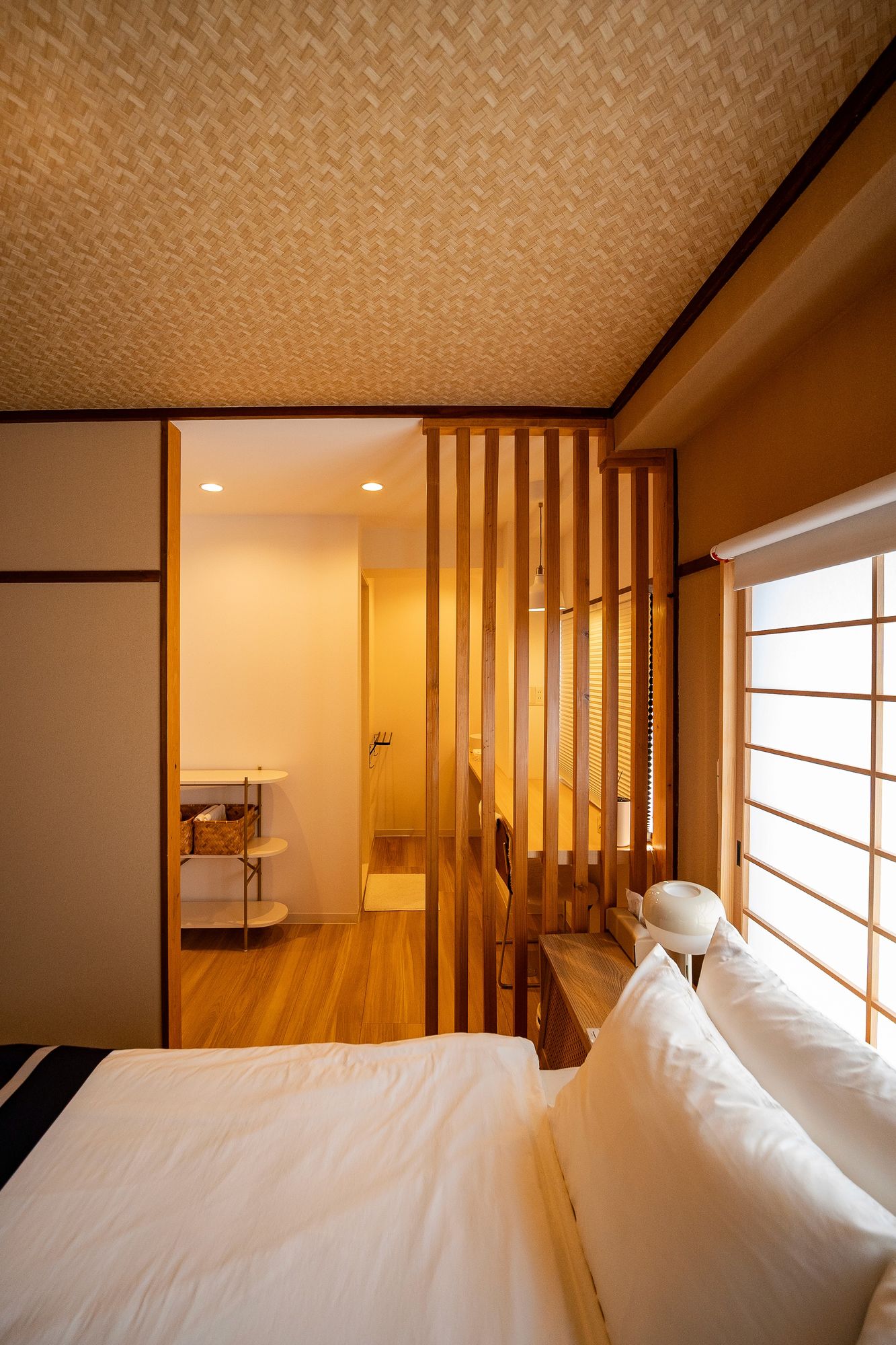 Bed beside a slatted screen and a shoji window