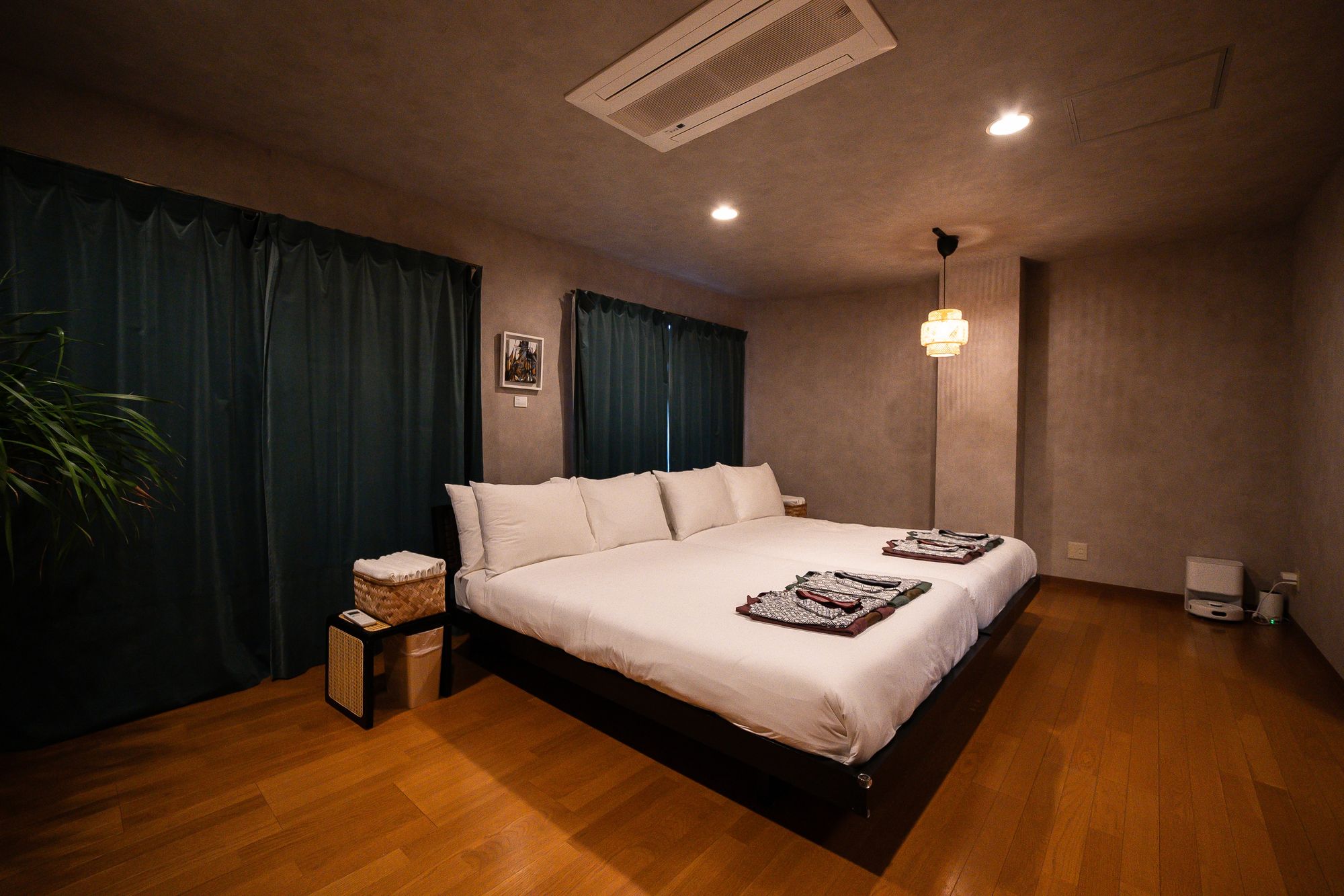 Bedroom with a low bed, dark drapes and a paper lantern