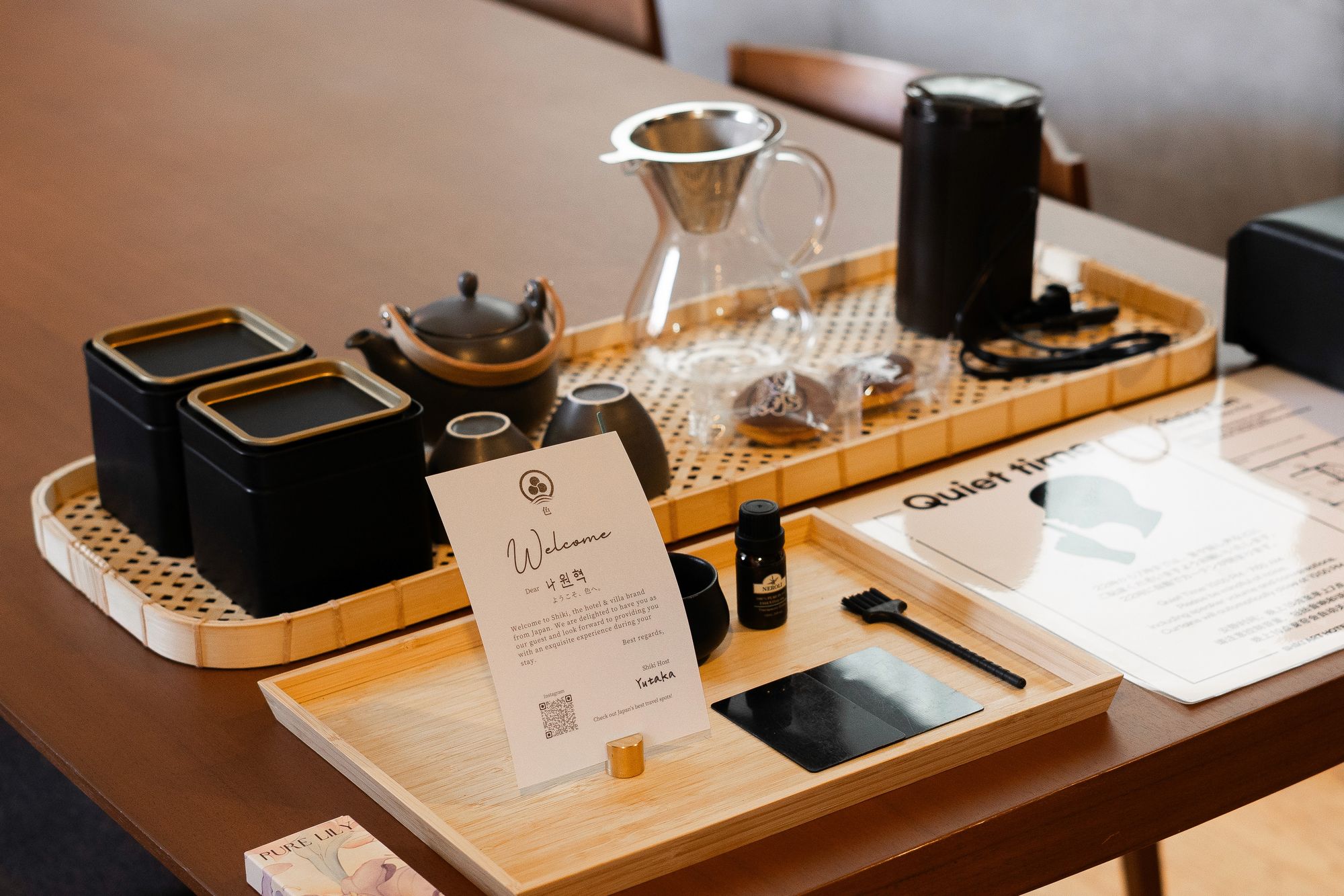 Welcome tray with teaware, a welcome card and amenities on a dark wooden dining table