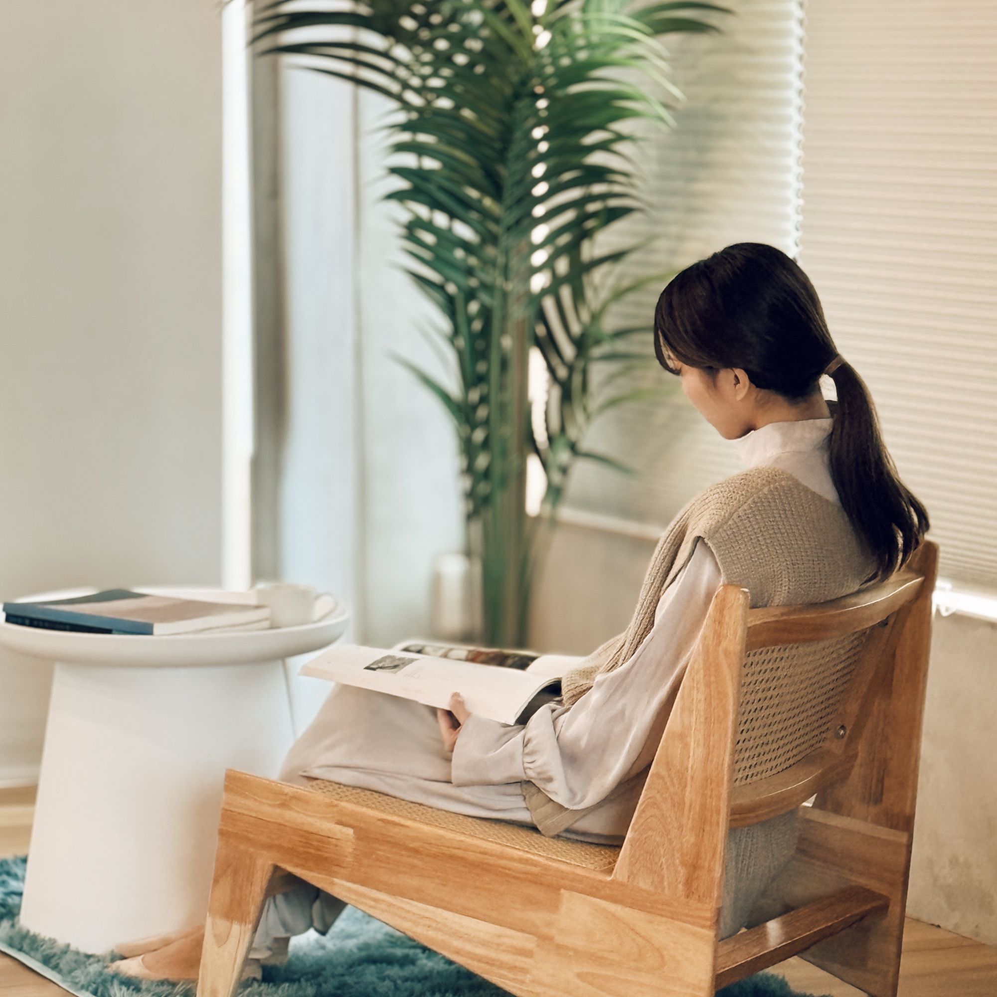 A guest reading in a wooden chair beside a palm