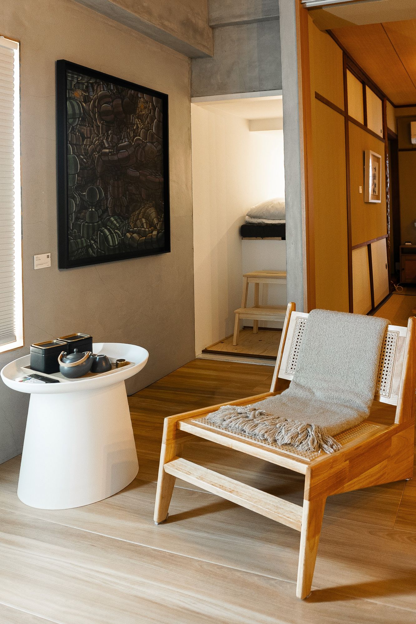 Lounge chair and low round table beside a framed artwork