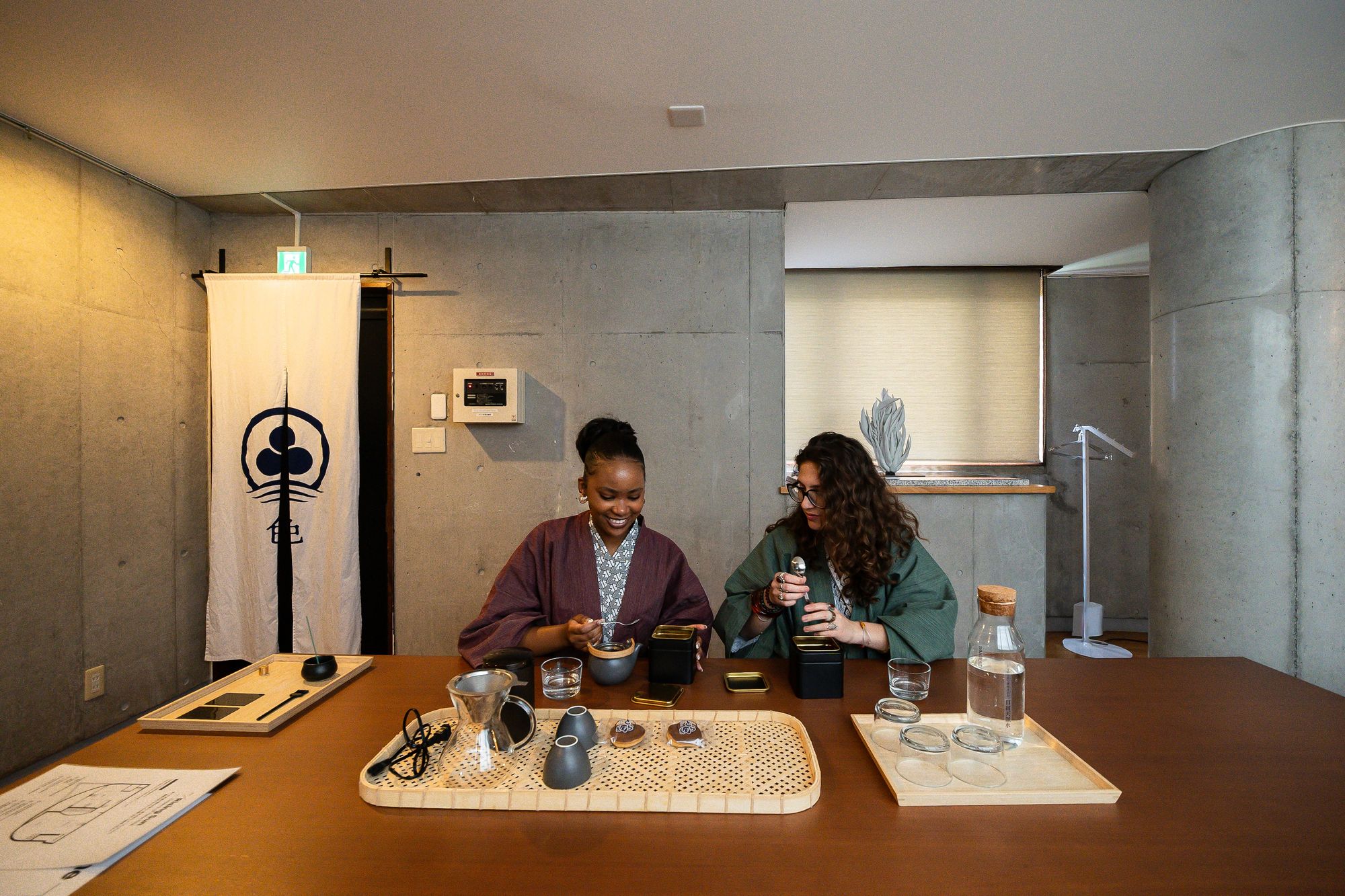 Two guests preparing tea and coffee at a long wooden table