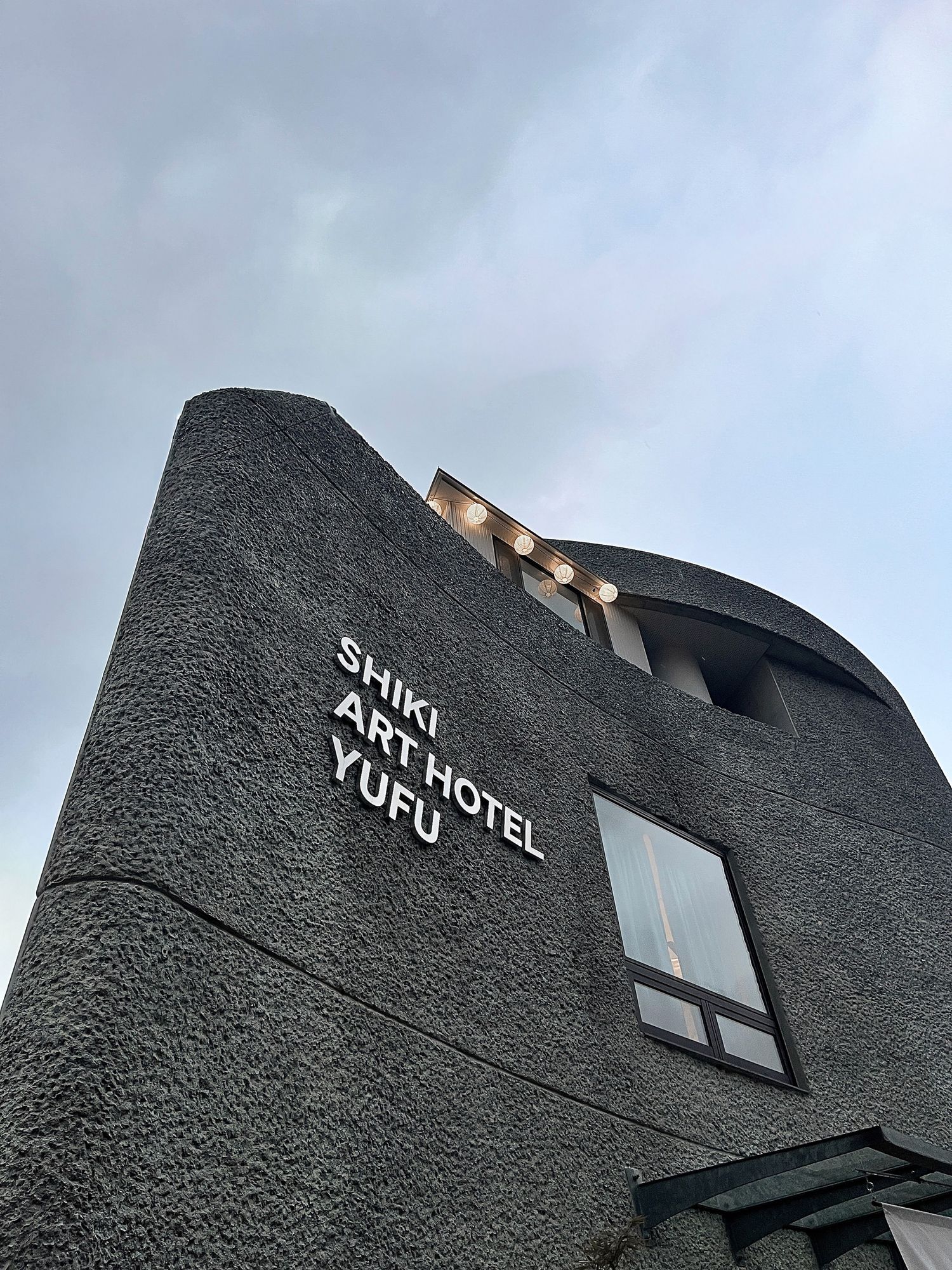 SHIKI ART HOTEL YUFU facade against a blue-grey sky