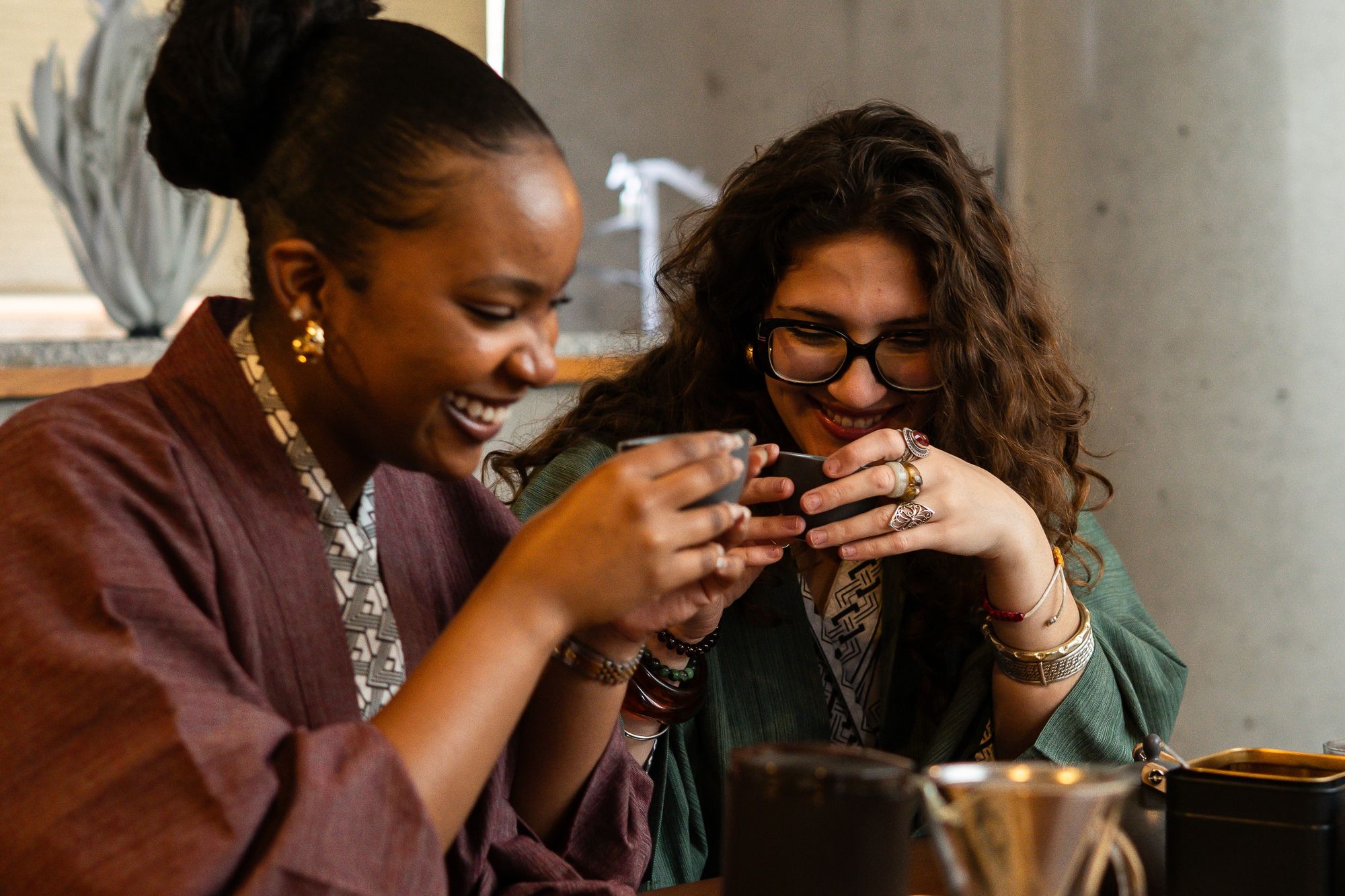 Two guests laughing over cups at a table